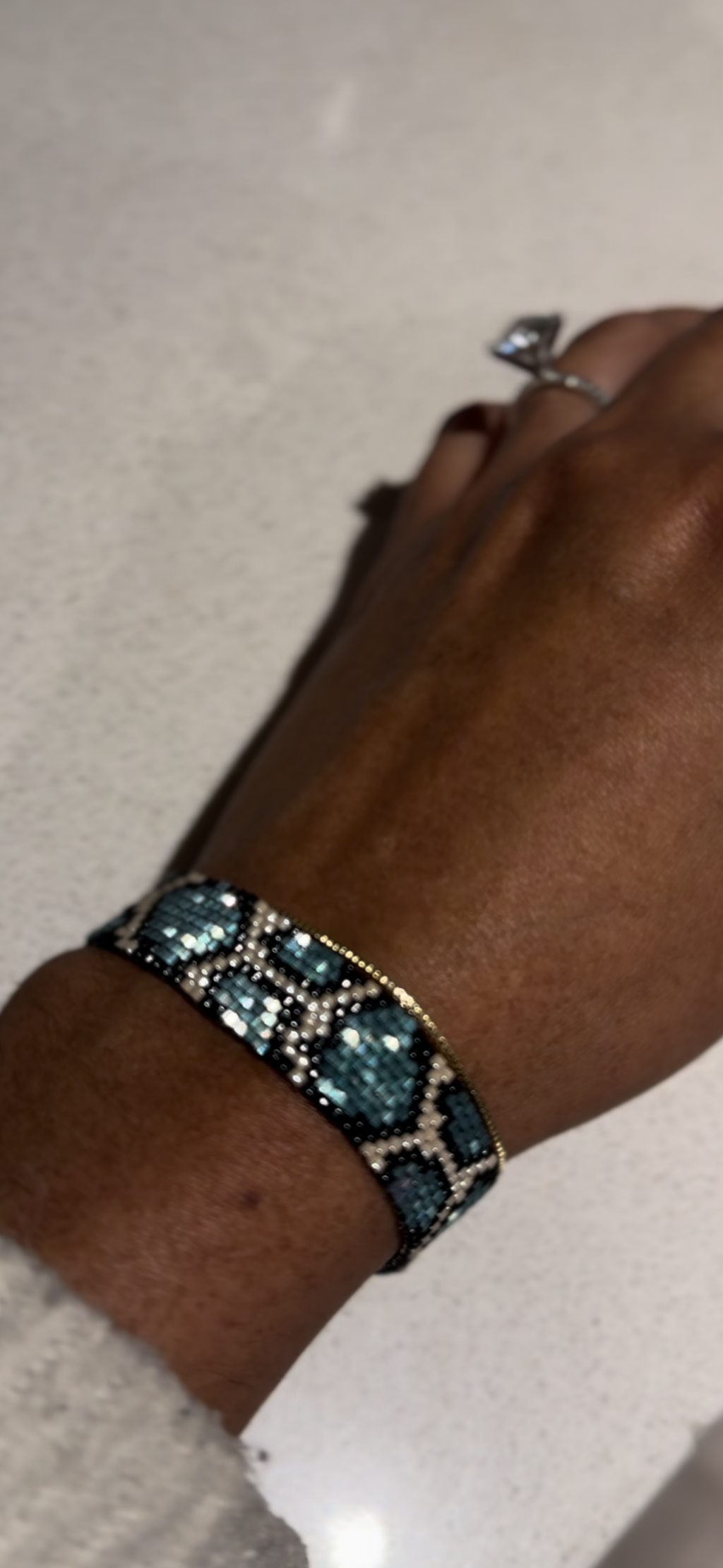 Hand wearing a bracelet with blue stones on a neutral background