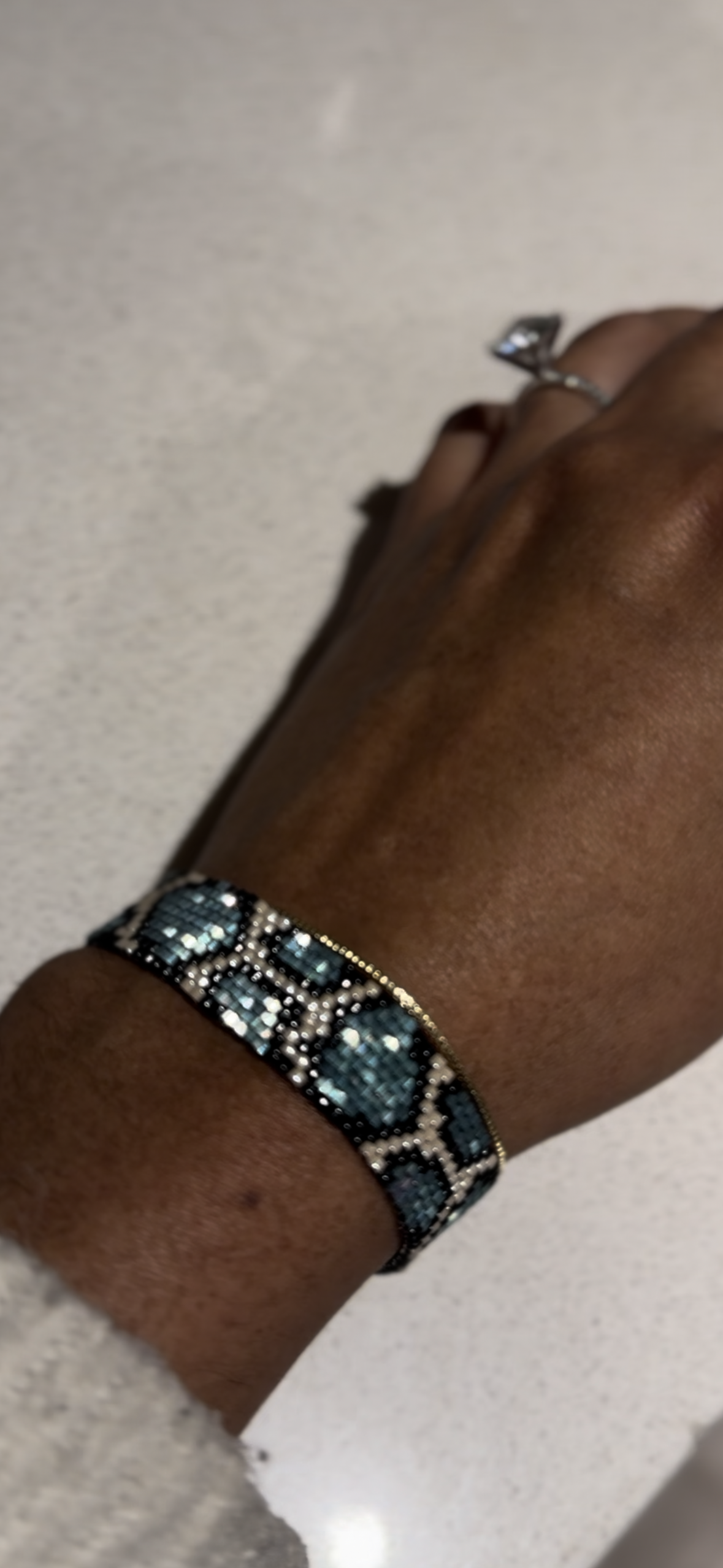 Hand wearing a bracelet with blue stones on a neutral background